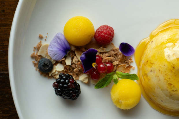 A white plate featuring a colorful assortment of berries and other fruits arranged as a dessert.