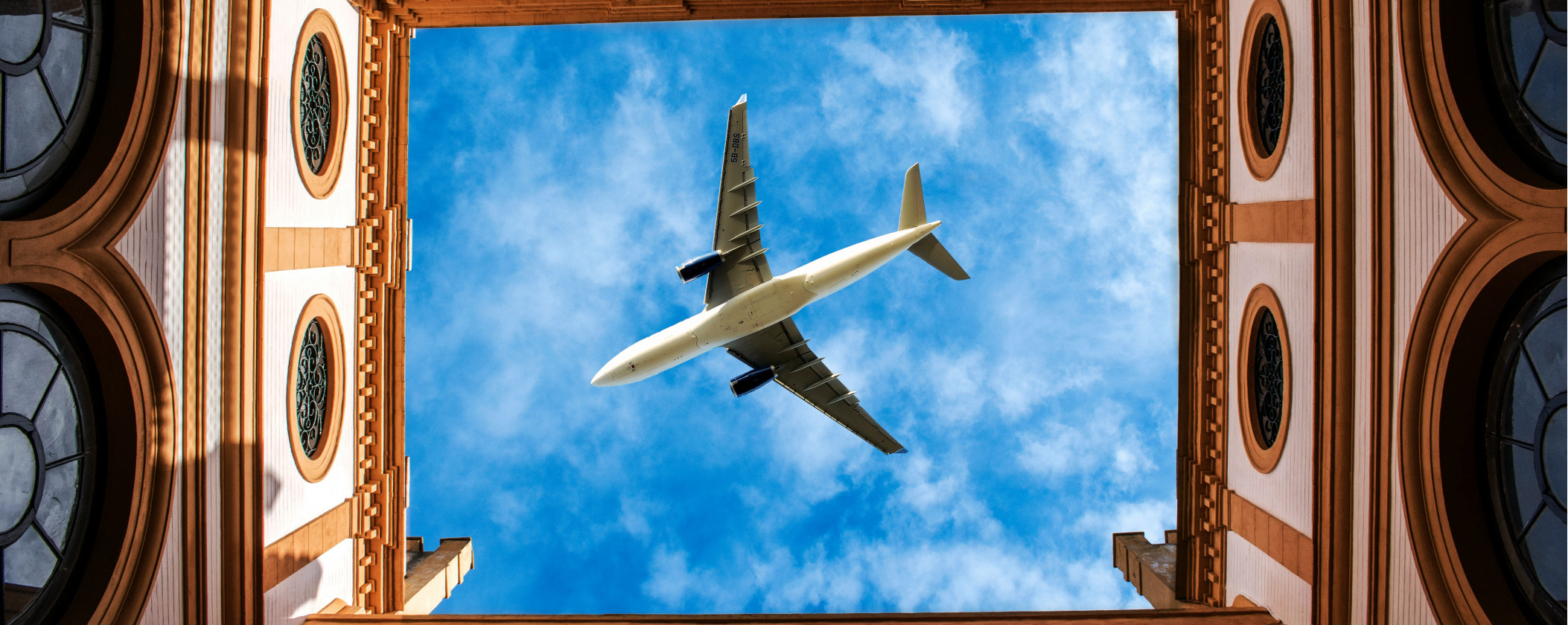 A plane flying through a building, with large windows visible on the structure's facade.